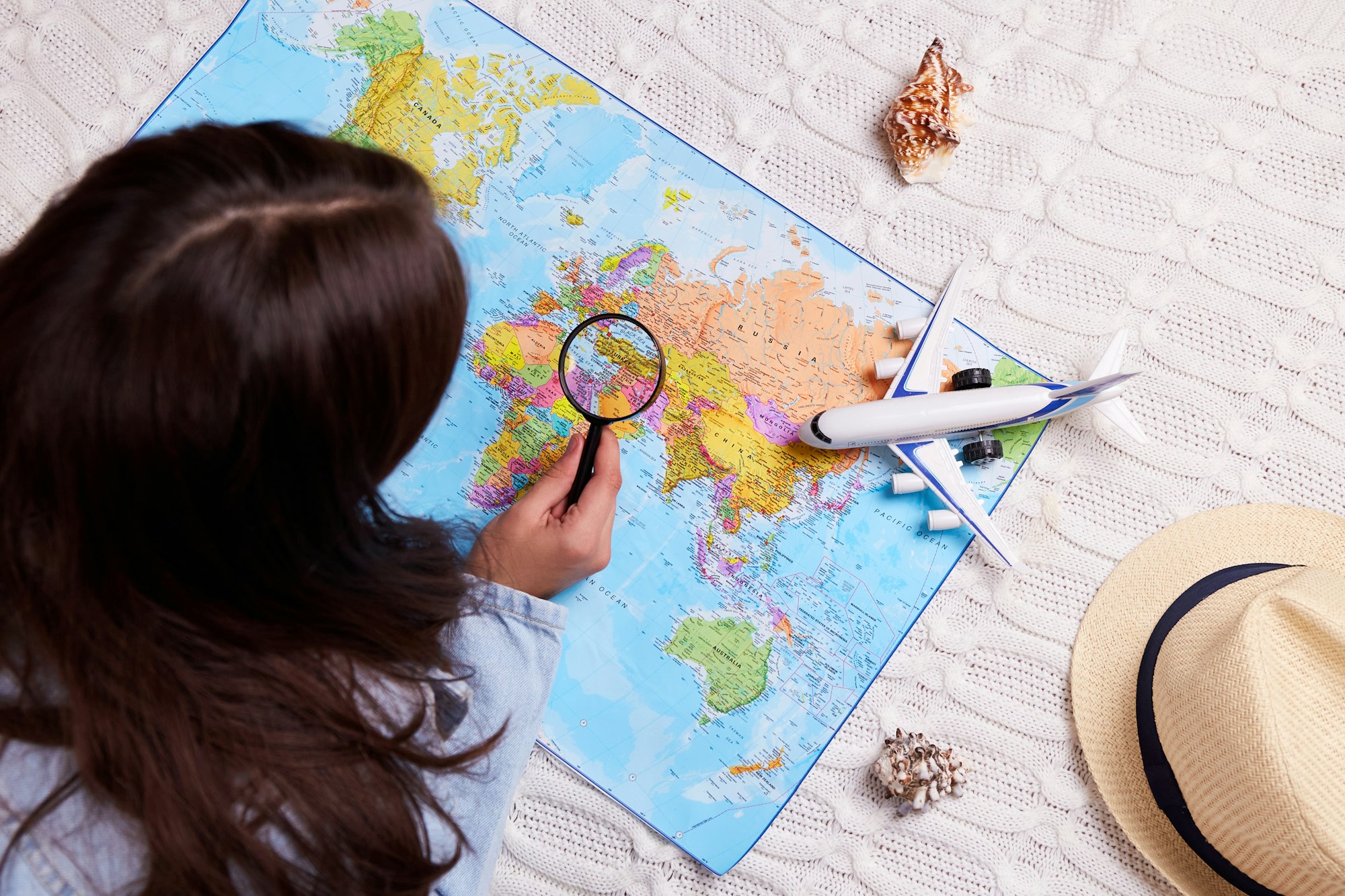 The girl explores the world map with a magnifying glass.